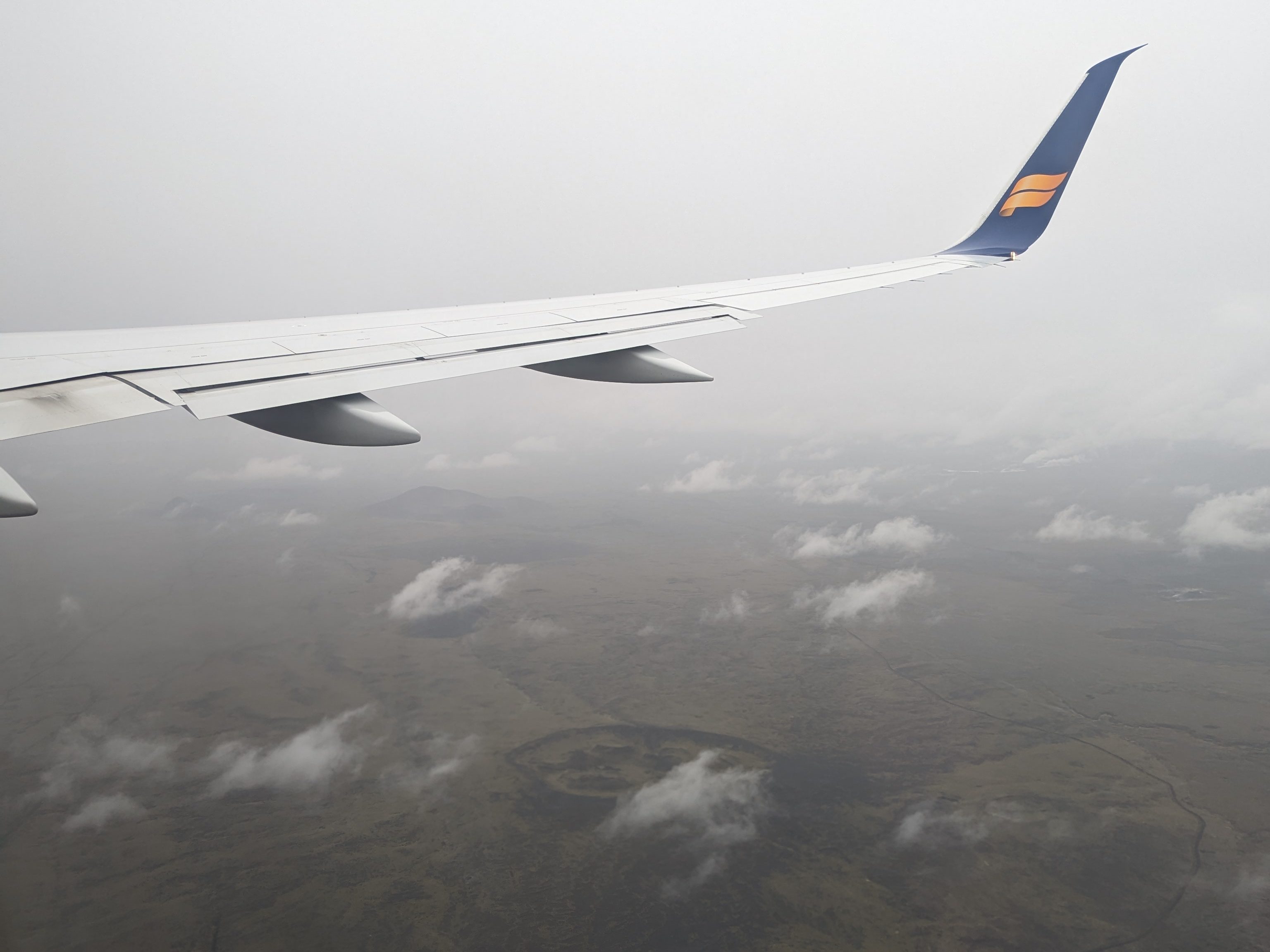Flying over Iceland’s dark green landscape on the way to Keflavik airport on Icelandair