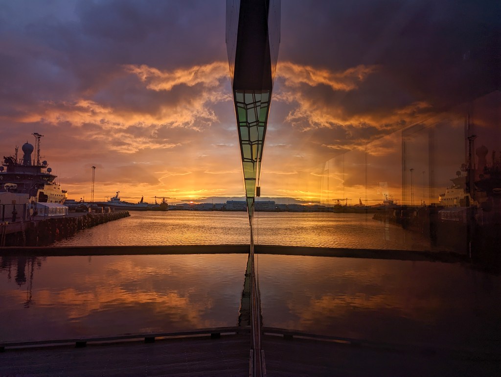 The midnight sunset reflecting off of the Harpa Concert Hall in Reykjavik, Iceland 